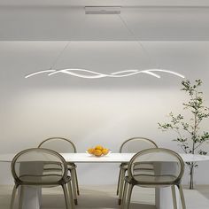 a white table with four chairs and a bowl of fruit on it in front of a wall