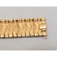 This is part of Chairish’s Costume Jewelry assortment.  Goldtone textured and smooth Asian inspired "waves" articulated bracelet with box clasp and security chain. Marked crown "TRIFARI." Measures: 7 1/4 inches long by 1 inch wide. Condition: Very good; light surface wear in places and a spot of goldtone loss to the back of part of the box clasp. An identical bracelet was featured in a 1959 advertisement. Formal Gold Link Bracelet With Bracelet Strap, Formal Metal Bracelet With Rectangular Links, Formal Link Bracelet Strap Jewelry, Formal Link Bracelet Jewelry, Formal Link Bracelet With Strap, Adjustable Formal Chain Bracelet With Clasp, Adjustable Chain Bracelet With Clasp For Formal Occasions, Vintage Formal Bracelet With Box Clasp, Elegant Metal Chain Bracelet With Clasp