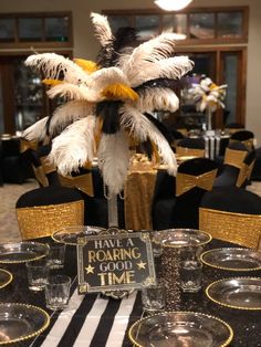 a table set up with black and white decorations, gold rimmed glasses and place settings