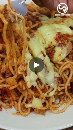 someone is serving spaghetti with cheese and sauce on a white plate while holding a fork