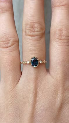 a woman's hand with a gold ring and blue stone on the middle finger