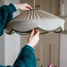 a woman is holding a lamp in front of her face while hanging it from the ceiling