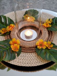 a candle is lit on top of a table with flowers and leaves around it,