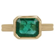 Displayed is a stunning East-to-West emerald solitaire engagement or right-hand ring in 14K yellow gold. This gorgeous solitaire ring carries a 2.75-carat emerald in a bezel setting. Fully faceted, this gemstone showcases excellent shine and beautiful, mossy medium green color. The emerald has very good clarity with minor flaws that are normal in all genuine emeralds! An ideal solitaire, perfect for everyday use! Setting Style: Bezel Setting Material: 14K Yellow Gold Setting Weight: 6.3 Grams Main Stone: Emerald Shape: Emerald Cut Weight: 2.75-Carats Clarity: Semi-Transparent Color: Medium Mossy Green Luster: Very Good Treatments: Natural, Oiling Origin: Zambia Estimated Retail Value: $14,490.00 USD Emerald Bezel Ring, Emerald Anniversary, Emerald Gem, Mossy Green, Split Shank Ring, Solitaire Setting, Bezel Ring, Ring Emerald, Right Hand Rings