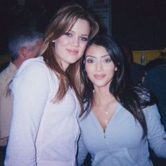 two beautiful young women standing next to each other in front of a table full of people