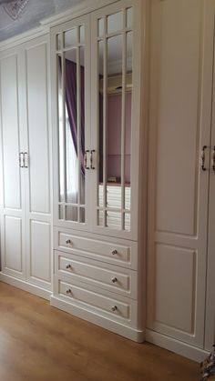 an empty room with white cabinets and wood flooring on the side, along with purple curtains