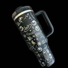 a black and white cup with skulls on it is shown in front of a black background