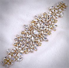 Add a touch of classic elegance to your bridal gown with this sparkling beaded belt! Adorned with an array of glowing crystals on a yellow gold base, it will give your dress an extra touch of glam to finish off your perfect look on your wedding day.The crystal appliqué measures approx. 12" long by 2 1/4" wide. It can be ordered as appliqué only to be sewn onto your dress, or attached to your choice of white or ivory double-faced satin ribbon, 1.5" wide and with a total length of 3 yards (108").