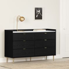 a black dresser with gold handles in a white room