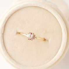 an engagement ring with a pink tourmaline stone on it in a white box