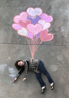 a woman laying on the ground with some balloons