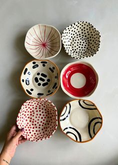 four bowls with different designs on them and one being held up by a person's hand