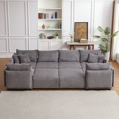 a large gray couch sitting on top of a wooden floor next to a white rug