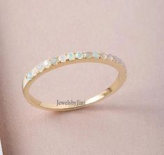 a yellow gold ring with white stones on the side and words jewelsbyjuni