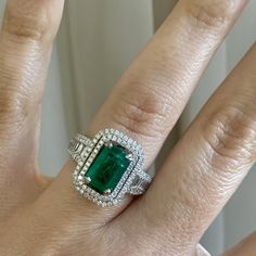 a woman's hand with an emerald and diamond ring