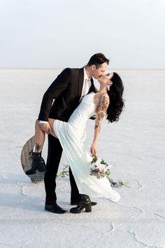 a bride and groom kissing in the snow