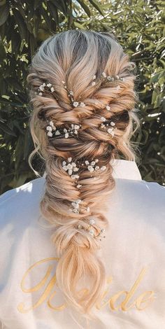 the back of a woman's head with braids and flowers in her hair