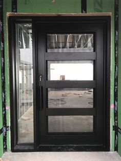 a black double door in front of a green wall under construction with scaffolding