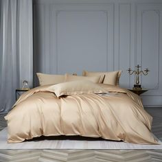 a bed with beige sheets and pillows in a room