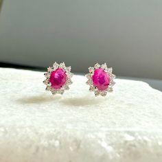 A timeless and classic design, symbolizing love, commitment and wealth. Perfect for everyday wear or dressed up for special occasions. Rubies are said to symbolize the sun, while its glowing hue suggests an inextinguishable flame within the stone. Add a pop of color with our Genuine Ruby and Diamond Solaris Earrings, available in 14k solid white gold and 14k solid yellow gold. Item Specifications: Materials: 14k Solid Gold  Gemstone: Natural Ruby Earring Diameter: 7.5 mm x 6.6 mm Ruby Diameter: Luxury Ruby Earrings With Prong Setting, Ruby Gemstone Diamond Earrings For Formal Occasions, Formal Ruby Gemstone Diamond Earrings, Timeless Hallmarked Diamond Earrings For Formal Occasions, 14k White Gold Earrings For Formal Occasions, Formal Round Diamond Earrings With Gemstones, Refined 14k Gold Earrings For Anniversary, Classic Pink Diamond Earrings For Formal Occasions, Luxury Round Halo Earrings