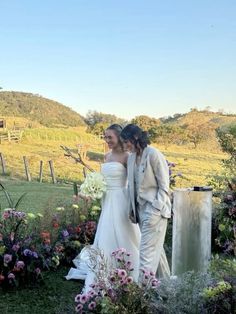 a bride and groom standing in front of flowers