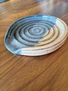 a blue and white plate sitting on top of a wooden table next to a cup