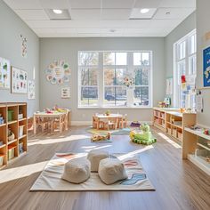 a child's playroom with lots of toys and books on the floor in front of large windows