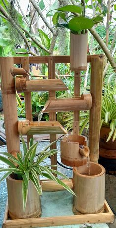 a bamboo water fountain with plants in pots on the side and another planter behind it