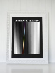 a white frame holding a black and white poster with the words different is beautiful on it