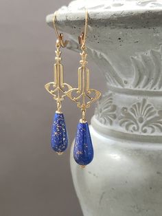 These 1920s inspired earrings feature ornate Art Deco style brass connectors and beautiful blue lampwork glass beads with gold foil accents. **PLEASE NOTE: Each glass bead is unique. So no two are exactly alike; each one is a little work of art. These earrings remind me of the exotic Art Deco fashion designs of Erte in the 1920s. The brass connectors are lightweight yet sturdy. These earrings measure 2 1/2 inches long and hang from gold plated lever back ear wires. Great accessory to pinch a lit Blue And Gold Art, 1920s Earrings, Gold Art Deco Earrings, Egyptian Revival Jewelry, Deco Fashion, Deco Earrings, Egyptian Revival, 1920s Art, Gold Art Deco