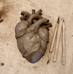 a heart shaped clay sculpture next to two crochet hooks