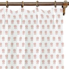 a curtain with pink flowers on it hanging from a wooden rodon over a window