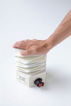 a hand is reaching for a stack of white papers on top of a small machine