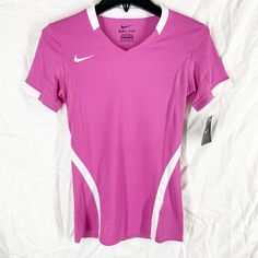 a women's pink nike shirt hanging on a hanger next to a white sheet