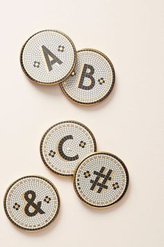 four coasters with letters and symbols on them sitting next to each other in front of a white background