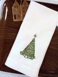 a white napkin with a green christmas tree on it sitting on top of a brown plate