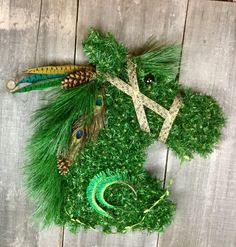 a stuffed animal made out of grass and feathers on top of a wooden table with pine cones