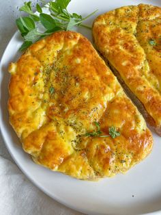 two pieces of bread sitting on top of a white plate next to a leafy green garnish