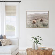 a living room filled with furniture and a painting hanging on the wall above a coffee table