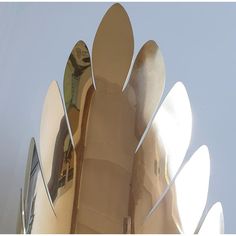 a large metal object with multiple mirrors on it's face and bottom part, in front of a blue sky