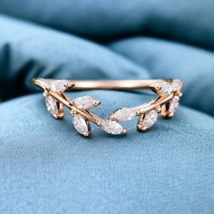 a close up of a ring on top of a blue cushioned surface with small leaves