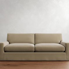 a couch sitting on top of a hard wood floor next to a white wall in an empty room