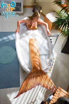 a woman laying on top of a towel next to a mermaid tail