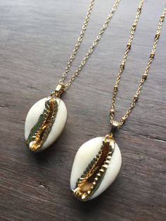 Cowrie Shell Necklace. This real cowrie shell has been dipped in 18k gold. It dangles from a gold-filled chain in your choice of a simple link or satellite chain. Wear it alone or layered for a great boho look. Matching bracelet available: https://www.etsy.com/listing/618535410/cowrie-shell-bracelet-adjustable?ref=shop_home_active_1 Matching earrings available here: https://www.etsy.com/listing/641824355/cowrie-shell-earrings-gold-cowrie-shell?ref=shop_home_active_2 Your cowrie shell necklace wi Shell-shaped Necklace With Adjustable Chain, Bohemian Gold Shell-shaped Jewelry, Gold Shell Jewelry With Adjustable Chain, Gold Shell-shaped Bohemian Necklace, Gold Shell-shaped Clavicle Chain Jewelry, Gold Shell Jewelry As A Gift, Gold Plated Shell-shaped Jewelry Gift, Gold Clavicle Chain Jewelry Shell-shaped, Gold Bohemian Shell Pendant Necklace