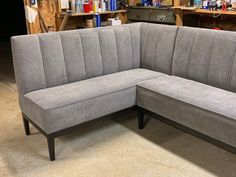 a gray couch with two separate seats in a room filled with shelves and other items