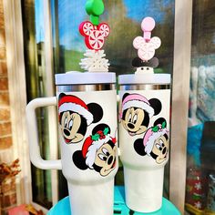 two mickey mouse christmas mugs sitting next to each other