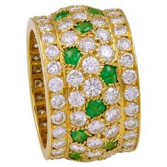 a gold ring with green and white stones on the inside, surrounded by smaller diamonds