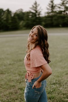 a woman standing in a field with her back to the camera and smiling at someone