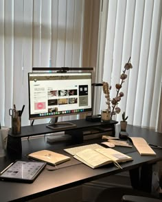 a computer monitor sitting on top of a desk next to a keyboard and notebooks