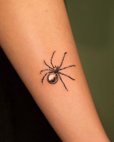 a black spider tattoo on the arm and leg, with a pearl in it's center